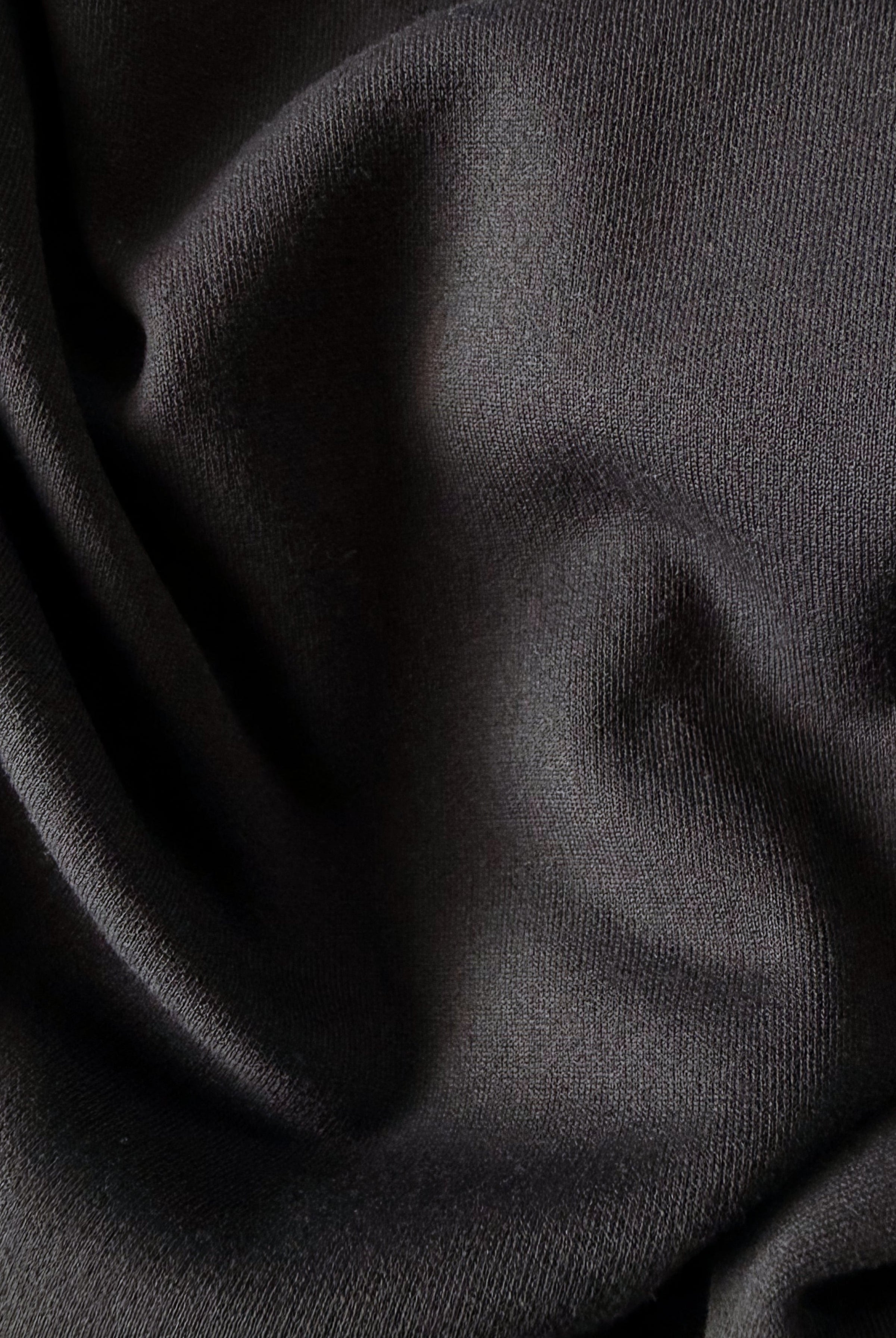 Macro close-up of TARANIRVANA garment in Phantom black, highlighting the premium SpiroTex™ luxury knit fabric texture with elegant drapes, quick-dry, moisture-wicking, odor-resistant, and UPF 50+ sun protection.