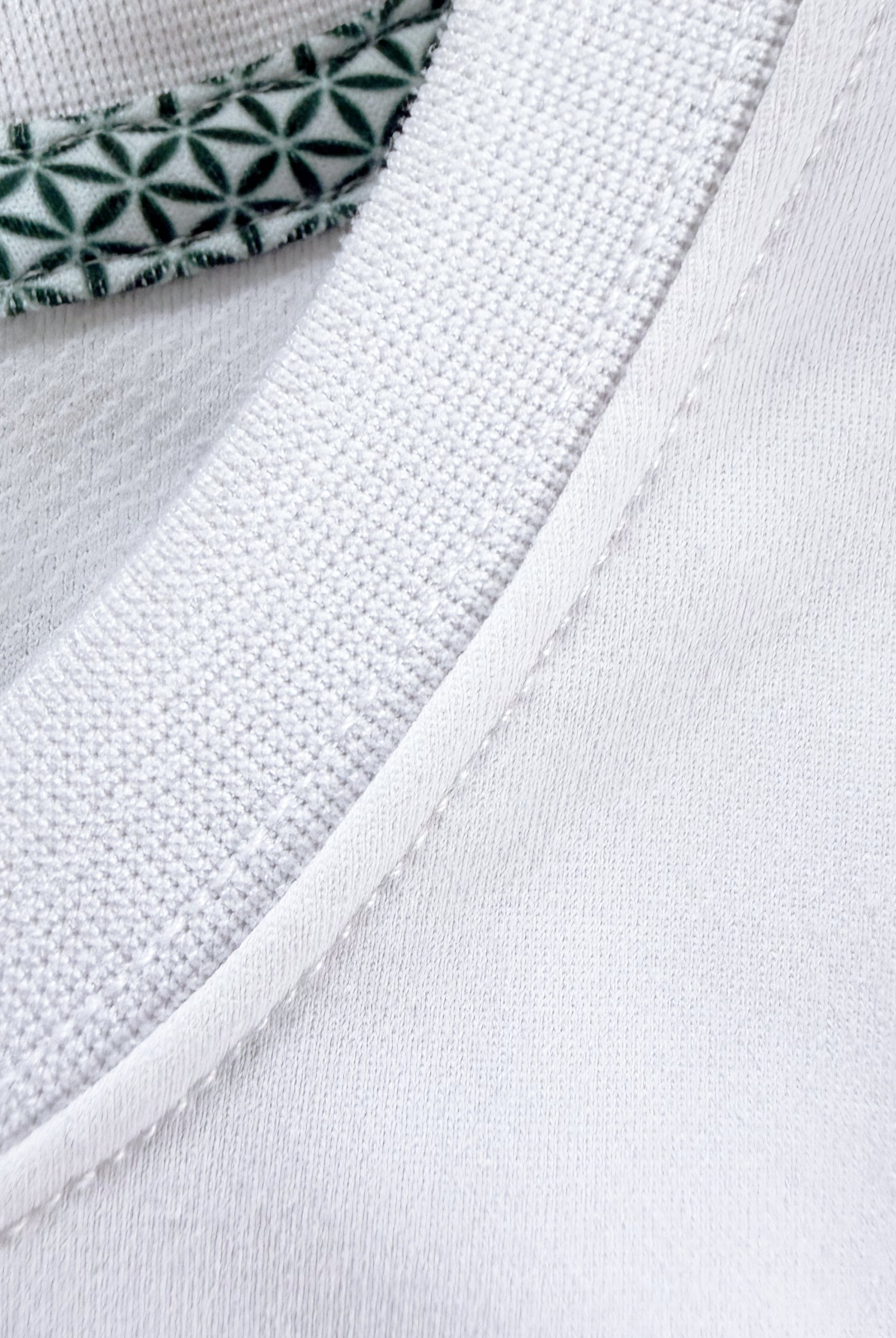 Close-up view of TARANIRVANA Porcelain white Essenza T-Shirt collar, highlighting the premium ribbed crewneck, refined stitching, and geometric patterned inner neck tape with quick-dry, moisture-wicking, odor-resistant, and UPF 50+ sun protection.