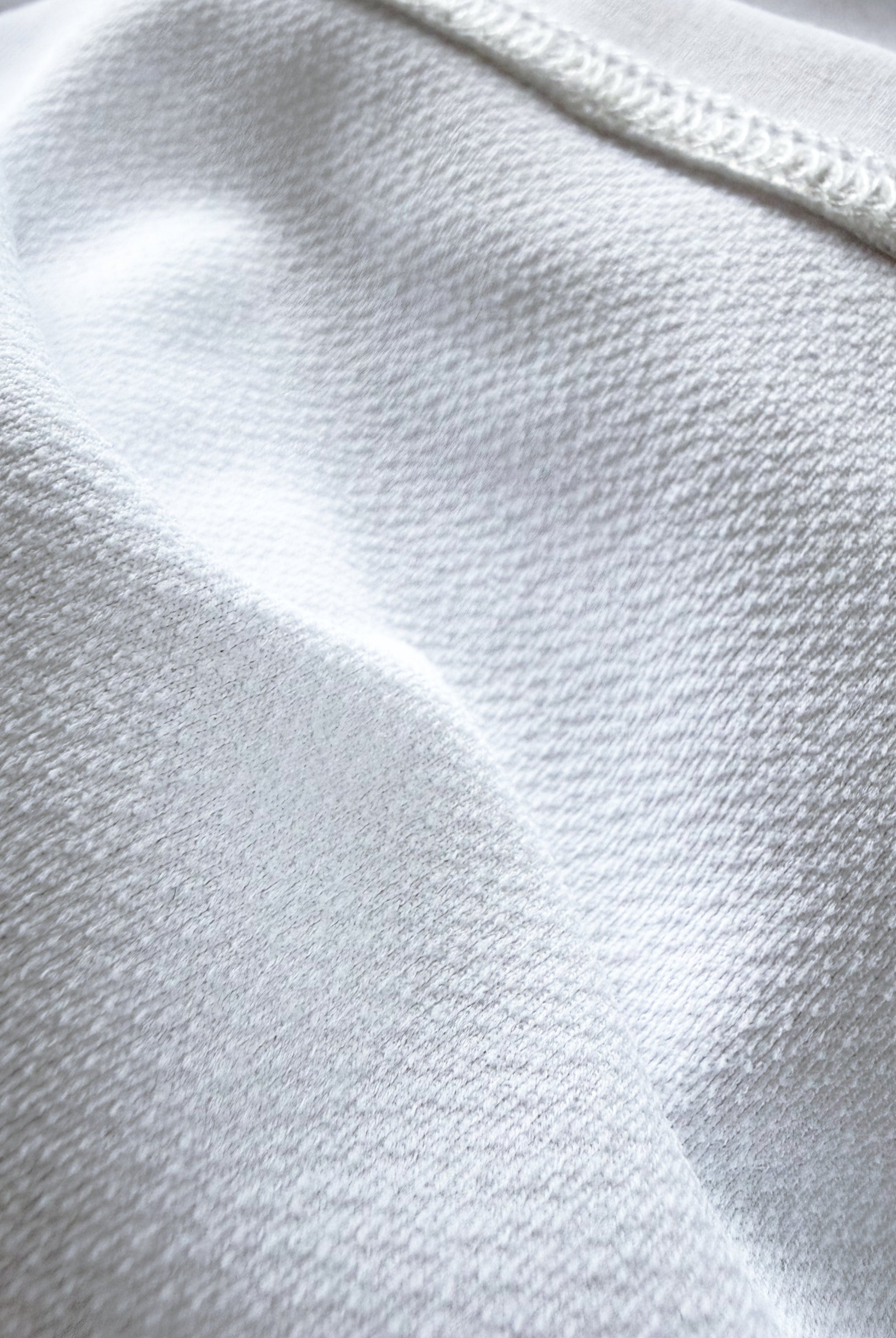 Macro close-up of the technical inner layer of TARANIRVANA Porcelain white garment, highlighting premium SpiroTex™ breathable knit texture and flatlock stitching with quick-dry, moisture-wicking, odor-resistant, and UPF 50+ sun protection.
