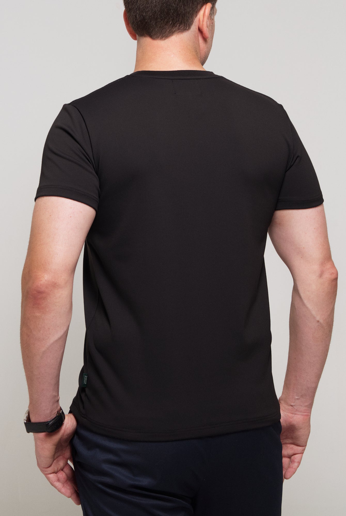 Back view of a man wearing TARANIRVANA Essenza T-Shirt in Phantom black, showcasing clean tailored shoulders and high-performance SpiroTex™ fabric with quick-dry, moisture-wicking, odor-resistant, and UPF 50+ sun protection.