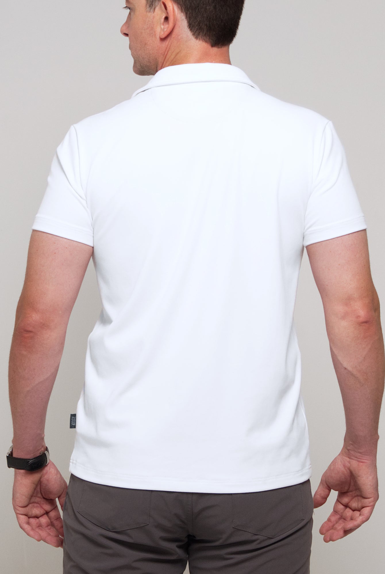 Back view of a man wearing TARANIRVANA Aria Polo in Porcelain white, showing clean tailored shoulders and high-performance SpiroTex™ fabric with quick-dry, moisture-wicking, odor-resistant, and UPF 50+ sun protection.