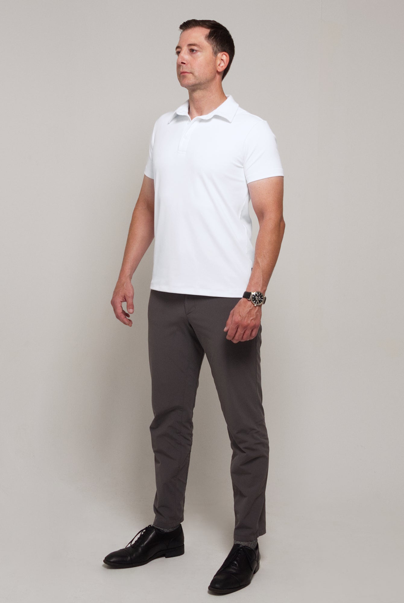 Full-length three-quarter view of a man wearing TARANIRVANA Aria Polo in Porcelain white, showcasing a sophisticated smart business silhouette in high-performance SpiroTex™ fabric with quick-dry, moisture-wicking, odor-resistant, and UPF 50+ sun protection.