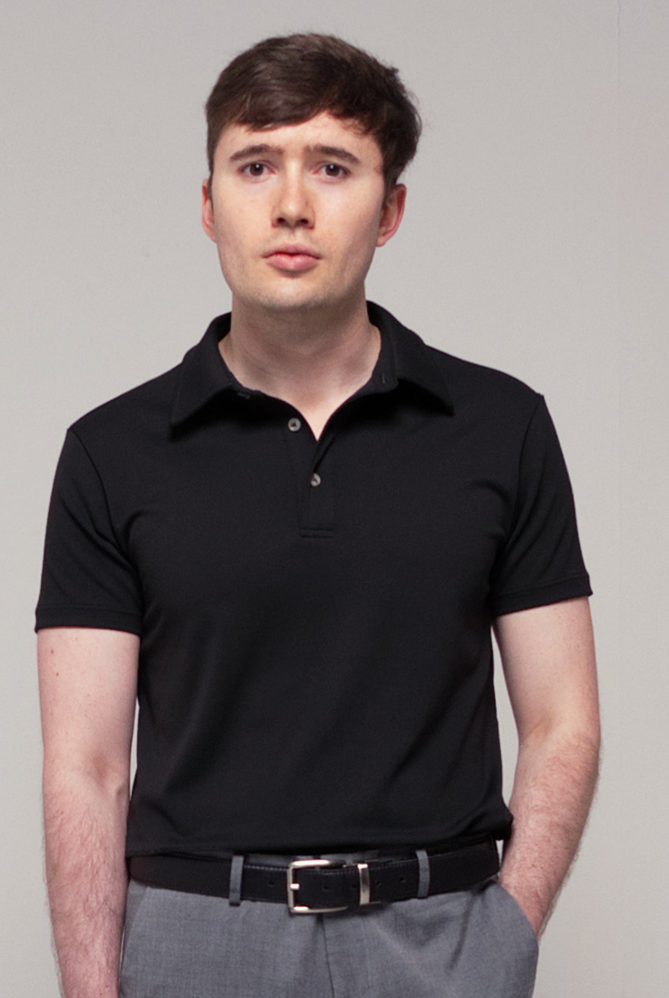 Front view of a man wearing TARANIRVANA Aria Polo in Phantom black, showcasing the minimalist collar design and high-performance SpiroTex™ fabric with quick-dry, moisture-wicking, odor-resistant, and UPF 50+ sun protection.