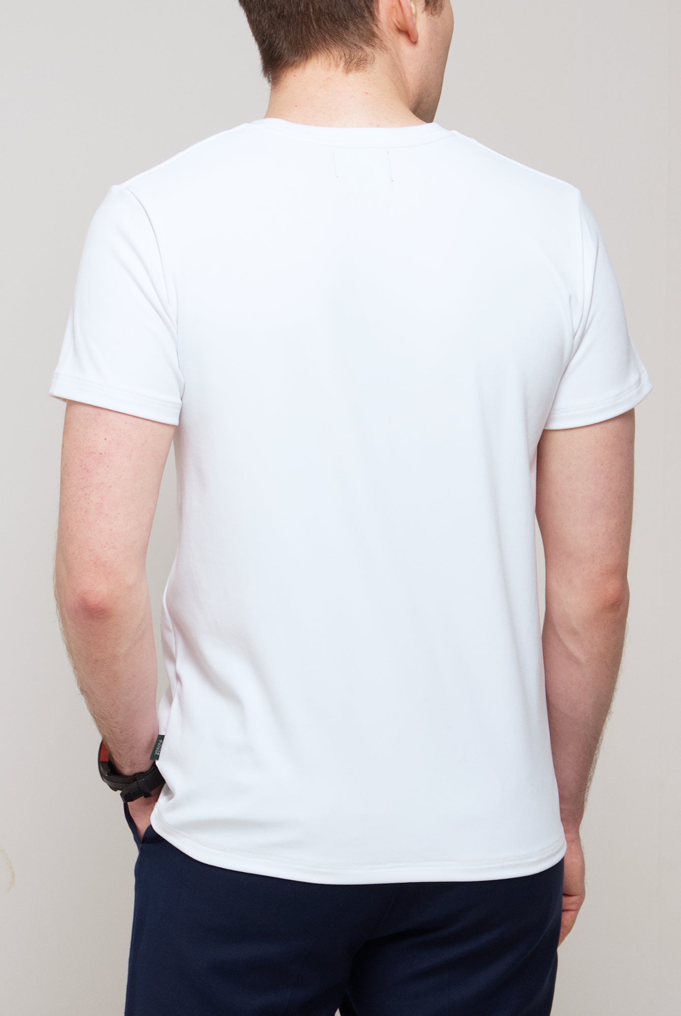 Cropped back view of a man wearing TARANIRVANA Essenza T-Shirt in Porcelain white, showcasing the clean shoulder tailoring and high-performance SpiroTex™ fabric with quick-dry, moisture-wicking, odor-resistant, and UPF 50+ sun protection.