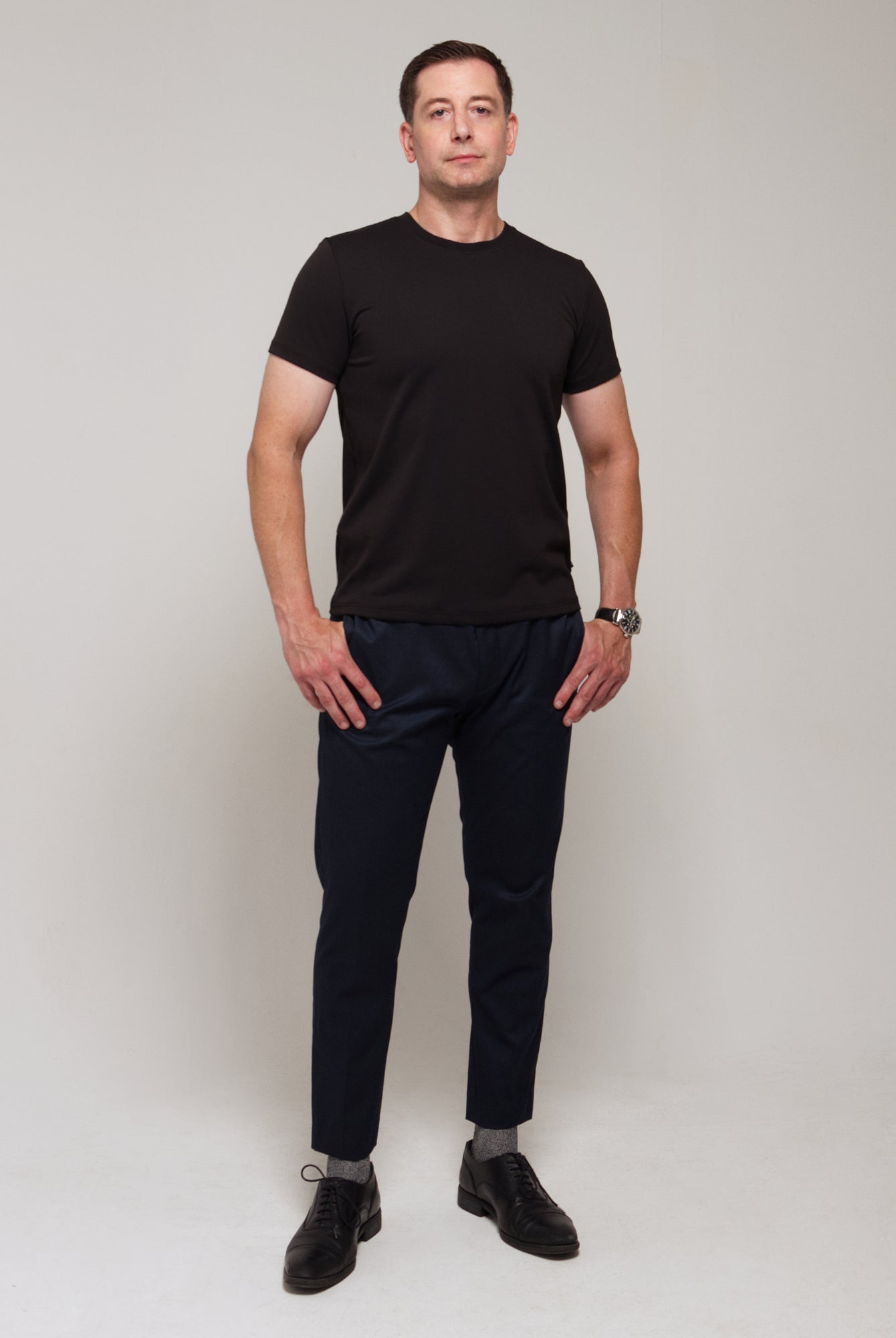 Front view of a man wearing TARANIRVANA Essenza T-Shirt in Phantom black, showcasing the classic crewneck and high-performance SpiroTex™ fabric with quick-dry, moisture-wicking, odor-resistant, and UPF 50+ sun protection.