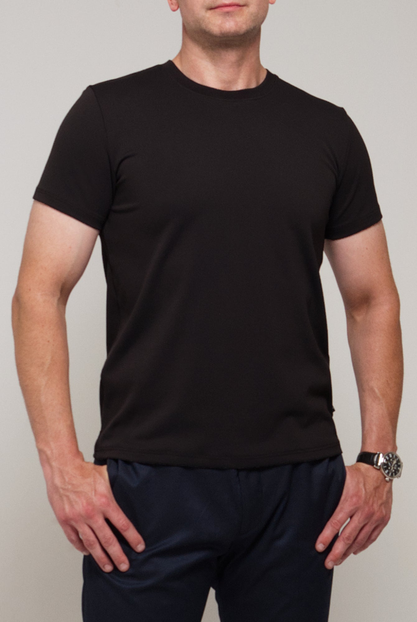 Front view of a man wearing TARANIRVANA Essenza T-Shirt in Phantom black, showcasing the classic crewneck and high-performance SpiroTex™ fabric with quick-dry, moisture-wicking, odor-resistant, and UPF 50+ sun protection.