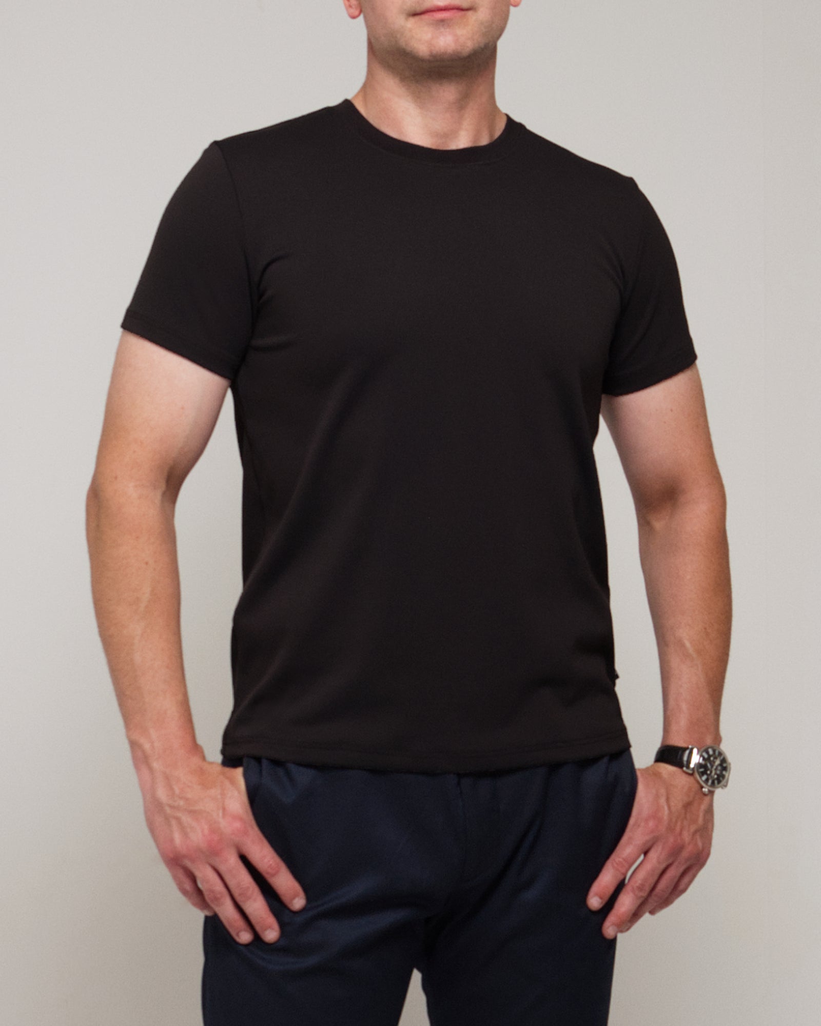 Front view of a man wearing TARANIRVANA Essenza T-Shirt in Phantom black, showcasing the classic crewneck and high-performance SpiroTex™ fabric with quick-dry, moisture-wicking, odor-resistant, and UPF 50+ sun protection.