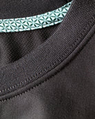 Close-up view of TARANIRVANA Essenza T-Shirt crewneck in Phantom black, highlighting the premium ribbed collar, green geometric pattern inner trim, and high-performance SpiroTex™ fabric with quick-dry, moisture-wicking, odor-resistant, and UPF 50+ sun protection.