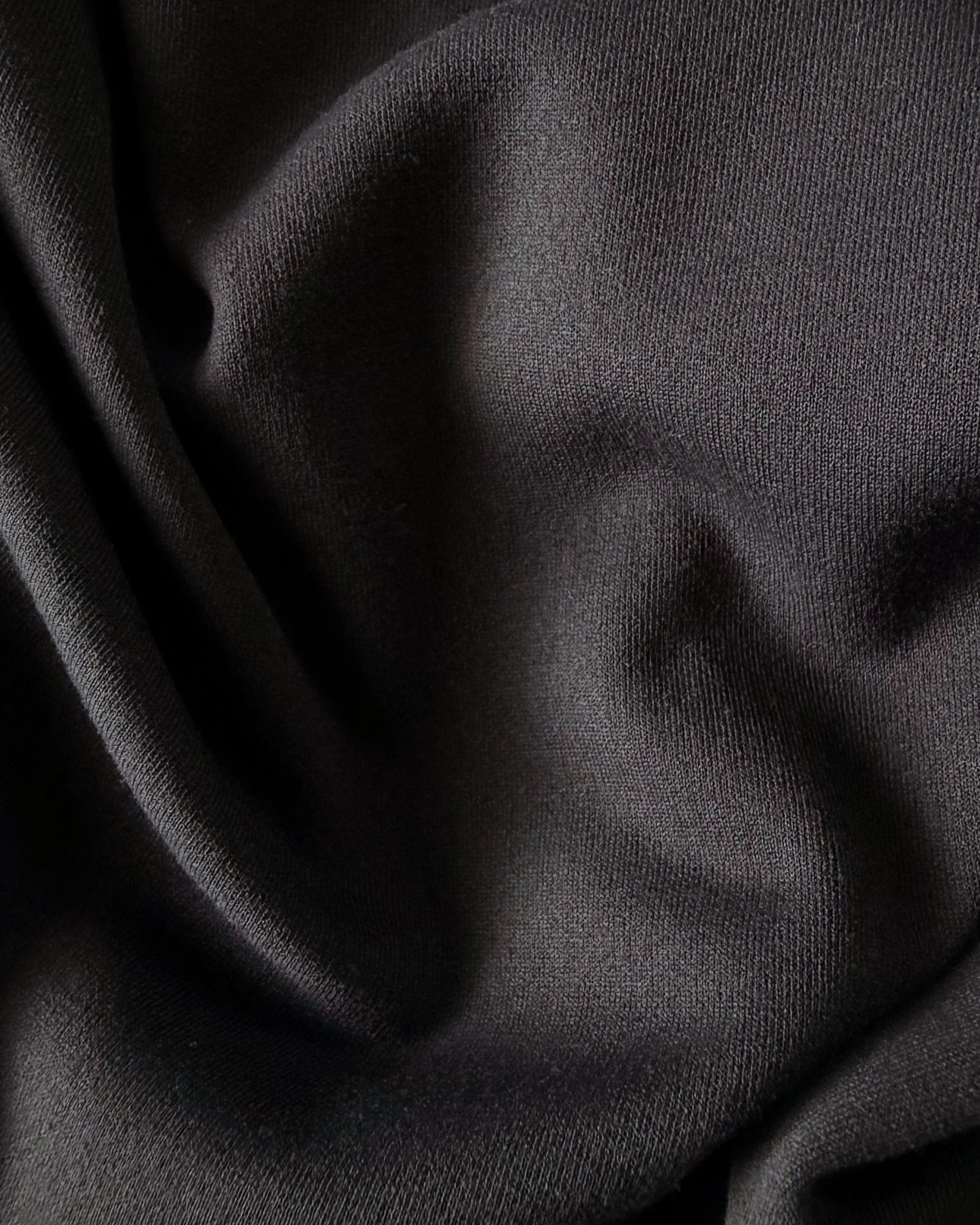 Macro close-up of TARANIRVANA garment in Phantom black, highlighting the premium SpiroTex™ luxury knit fabric texture with elegant drapes, quick-dry, moisture-wicking, odor-resistant, and UPF 50+ sun protection.