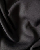 Macro close-up of TARANIRVANA garment in Phantom black, highlighting the premium SpiroTex™ luxury knit fabric texture with elegant drapes, quick-dry, moisture-wicking, odor-resistant, and UPF 50+ sun protection.