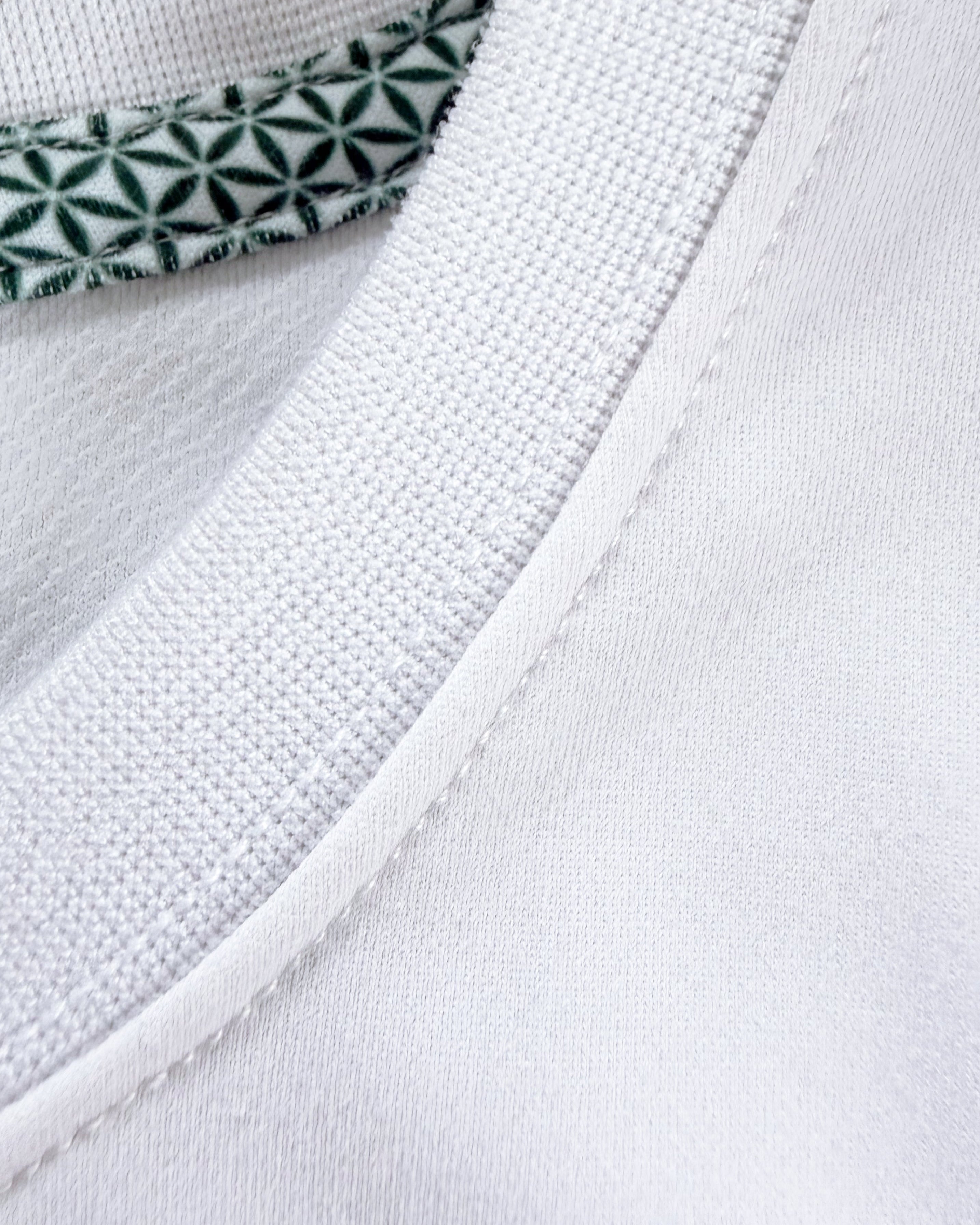 Close-up view of TARANIRVANA Porcelain white Essenza T-Shirt collar, highlighting the premium ribbed crewneck, refined stitching, and geometric patterned inner neck tape with quick-dry, moisture-wicking, odor-resistant, and UPF 50+ sun protection.