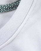 Close-up view of TARANIRVANA Porcelain white Essenza T-Shirt collar, highlighting the premium ribbed crewneck, refined stitching, and geometric patterned inner neck tape with quick-dry, moisture-wicking, odor-resistant, and UPF 50+ sun protection.