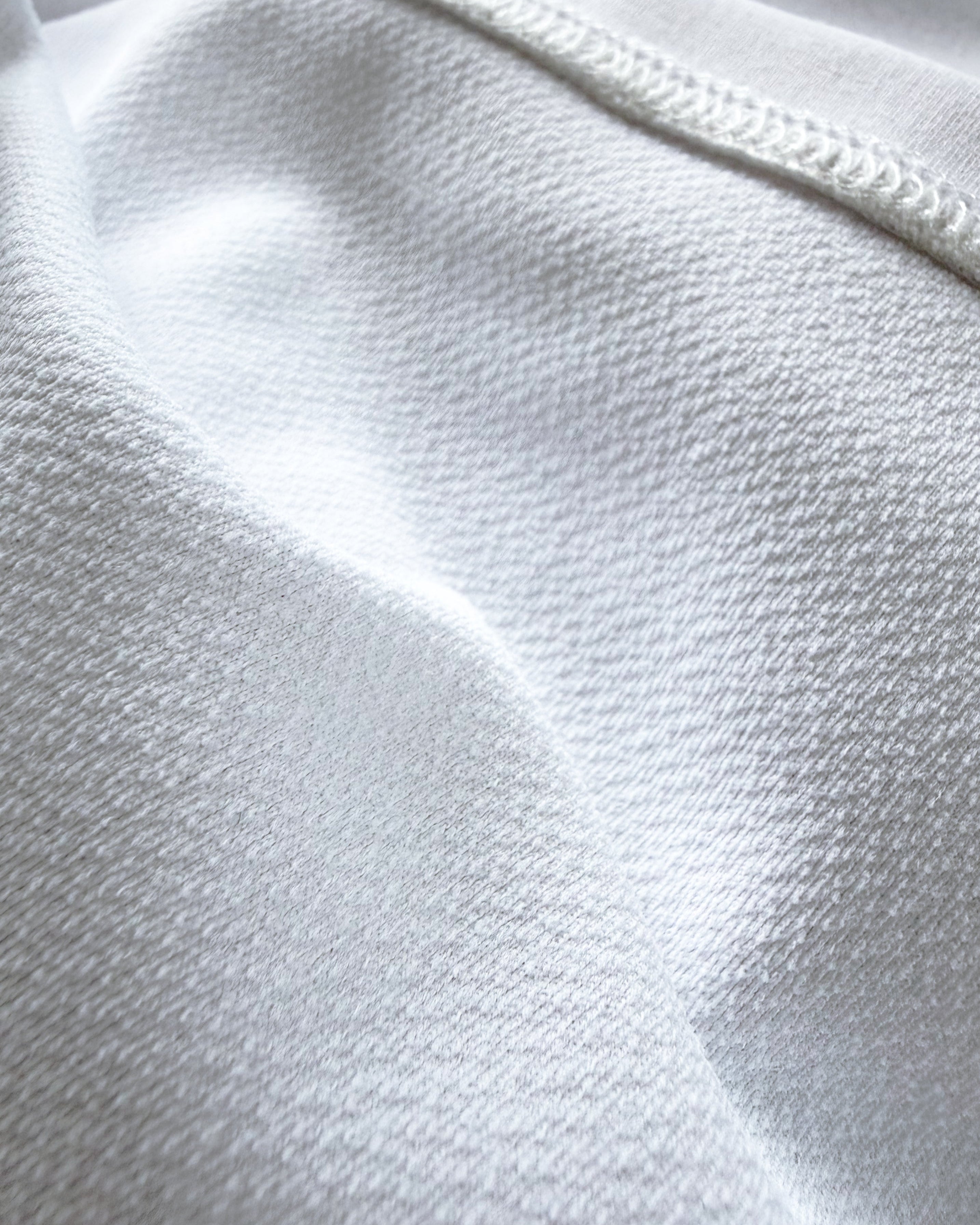 Macro close-up of the technical inner layer of TARANIRVANA Porcelain white garment, highlighting premium SpiroTex™ breathable knit texture and flatlock stitching with quick-dry, moisture-wicking, odor-resistant, and UPF 50+ sun protection.