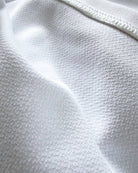 Macro close-up of the technical inner layer of TARANIRVANA Porcelain white garment, highlighting premium SpiroTex™ breathable knit texture and flatlock stitching with quick-dry, moisture-wicking, odor-resistant, and UPF 50+ sun protection.