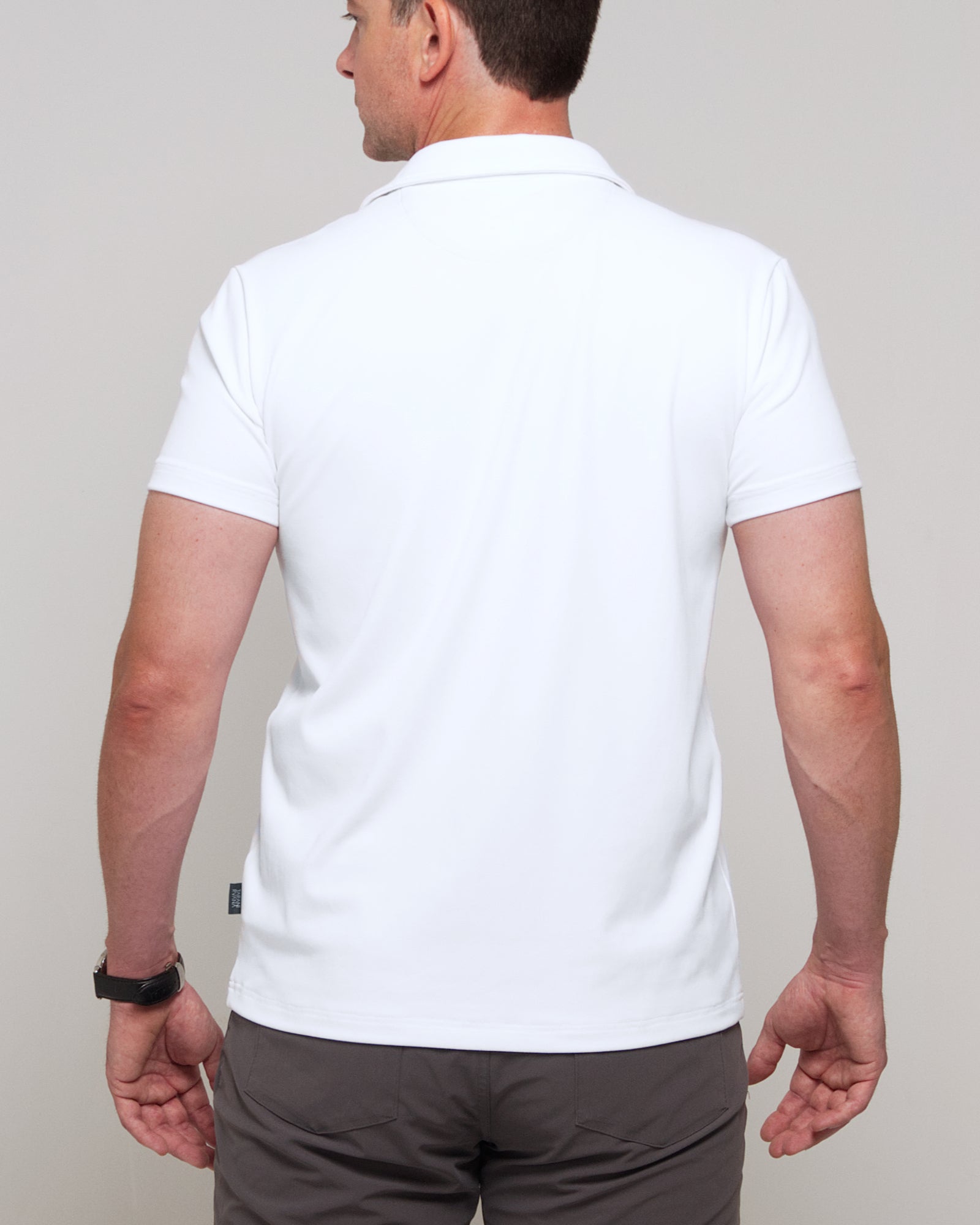 Back view of a man wearing TARANIRVANA Aria Polo in Porcelain white, showing clean tailored shoulders and high-performance SpiroTex™ fabric with quick-dry, moisture-wicking, odor-resistant, and UPF 50+ sun protection.