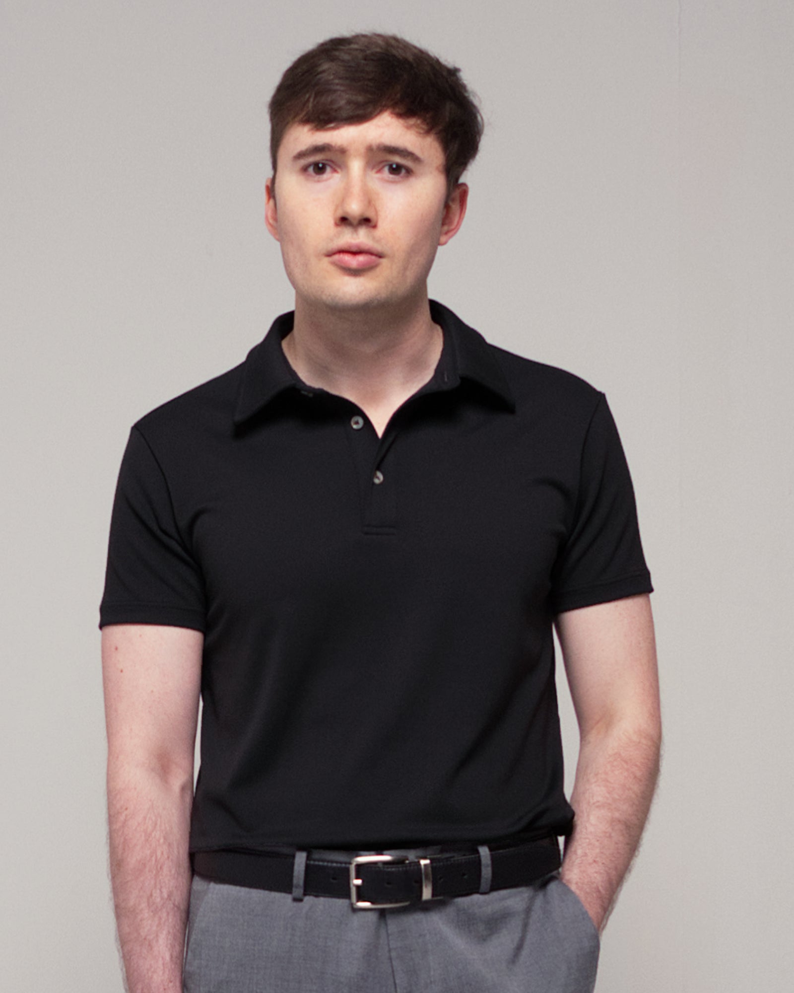 Front view of a man wearing TARANIRVANA Aria Polo in Phantom black, showcasing the minimalist collar design and high-performance SpiroTex™ fabric with quick-dry, moisture-wicking, odor-resistant, and UPF 50+ sun protection.