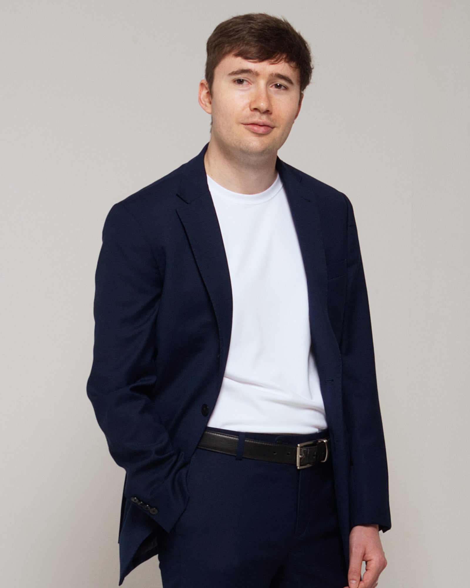 Three-quarter front view of a man wearing TARANIRVANA Essenza T-Shirt in Porcelain white, showcasing a sophisticated smart business silhouette in high-performance SpiroTex™ fabric with quick-dry, moisture-wicking, odor-resistant, and UPF 50+ sun protection.
