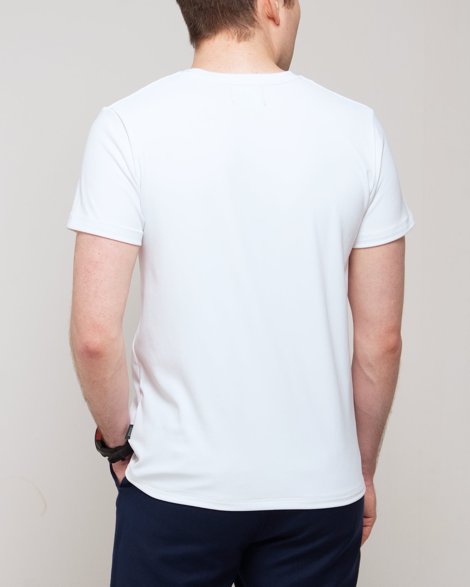 Cropped back view of a man wearing TARANIRVANA Essenza T-Shirt in Porcelain white, showcasing the clean shoulder tailoring and high-performance SpiroTex™ fabric with quick-dry, moisture-wicking, odor-resistant, and UPF 50+ sun protection.