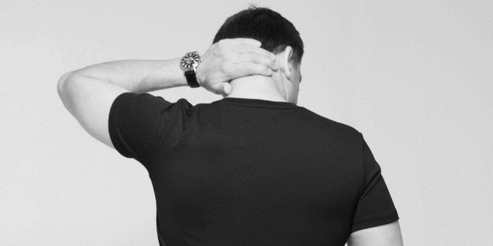Black and white back view of a man wearing TARANIRVANA Essenza T-Shirt in Phantom black, serving as a homepage banner link to explore the men's collection featuring high-performance SpiroTex™ fabric with quick-dry, moisture-wicking, odor-resistant, and UPF 50+ sun protection.
